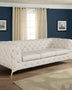 beige-tufted button sofa in a navy blue room